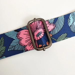 Detail showing blue floral woven shoulder strap with metallic buckle for handbags