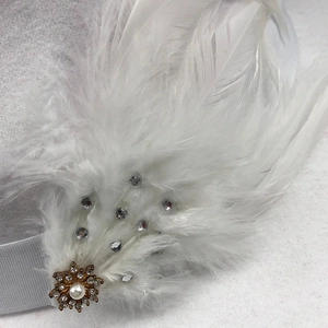 Detail von weißem Federkopfschmuck mit goldenem Blumenmetall und Perlenverzierung
