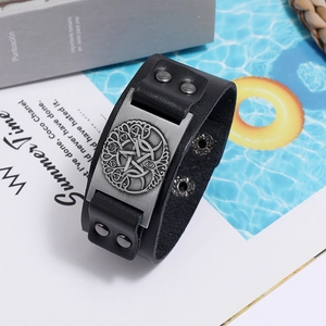 Detailed close-up of a black leather bracelet featuring a silver Tree of Life metal plaque