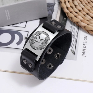 Close-up of vintage Viking Tree of Life metal plaque on wide black braided leather bracelet