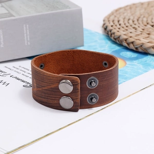 Detail of dark brown leather cuff with wood-grain texture and double snap buttons