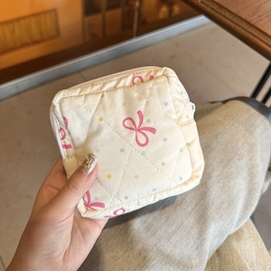 Handheld quilted beige pouch with pink bow and colorful polka dot print for travel
