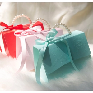 Wedding candy gift boxes with pearl handles and silk bows in red, pink and light blue colors
