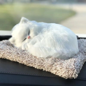 Close-up of fluffy white realistic sleeping cat toy resting on a brown plush cushion
