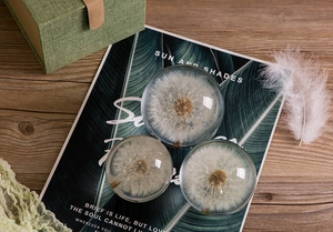 Three dandelion crystal spheres of different sizes on a rustic wooden desk with gifts