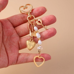 Detail of golden heart keychain with key charms and white imitation pearl beads strand
