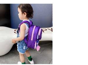 Toddler rocket backpack in purple with white stars pattern and side pocket on child