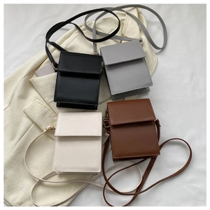 Flat lay of small square crossbody bags in black, grey, cream and brown faux leather