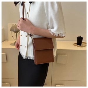 Brown faux leather crossbody bag worn by model in a cozy minimalist home interior