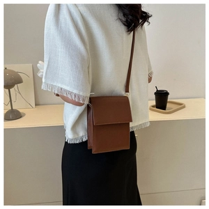 Brown PU leather crossbody bag with flap cover shown from a side view on a model