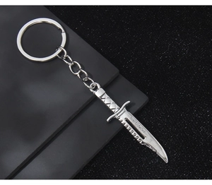 Silver metal tactical knife keychain detail with CROSSFIRE engraving and serrated blade edge