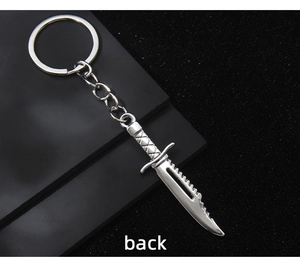 Close-up of a silver miniature knife keychain with serrated blade and textured handle