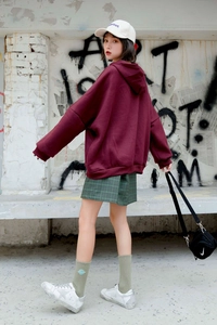 Street style view of loose dark red hoodie paired with olive green planet embroidery socks