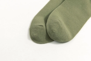 Close-up of green college style socks showing detailed knitting texture and toe stitching