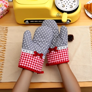 Close-up of thick checkered oven mitts with gray polka dots and red bows in a kitchen setting