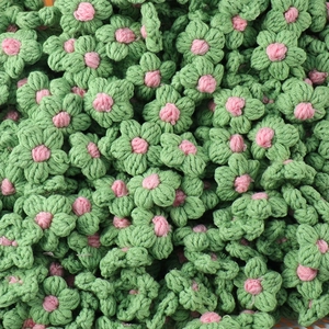 Macro detail of hand-knitted green flowers with pink centers made of soft woolen yarn