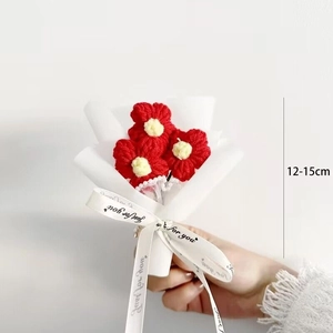 Close-up of handmade red knitted mini flower bouquet wrapped in white paper, 12-15cm height