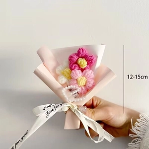 Close-up of handmade 12-15cm knitted yarn flower bouquet with pink wrap and pearl chain