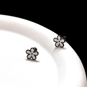 Macro view of minimalist black and white daisy floral earrings in high-grade titanium steel