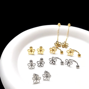 Detailed close-up of gold and silver flower stud earrings on a white ceramic tray