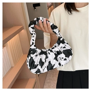 Close-up of a cloud-shaped shoulder bag featuring a stylish black and white cow print
