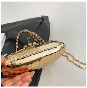 Close-up of gold wave patterned acrylic shell evening bag with metal chain strap