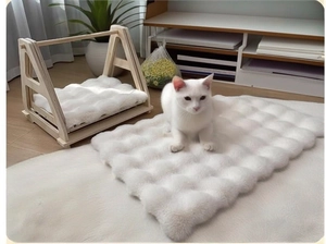 Close-up of thick white plush bubble fleece pet cushion on a solid wood cat bed frame