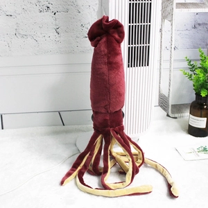 Realistic deep red squid plush toy with yellow tentacles on a soft white surface