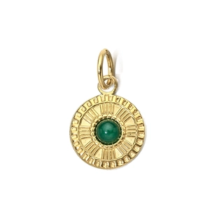 Detailed close-up of a vintage gold pendant with a green gemstone inlay and radial texture