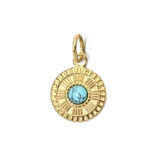 Detail of vintage gold-plated round pendant featuring a turquoise stone and sunburst motif
