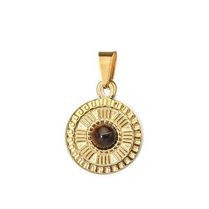 Detail of a vintage golden sunburst pendant with a center brown stone on white background
