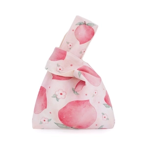 Detail of knot wrist bag featuring pink peach watercolor print on cream cotton fabric