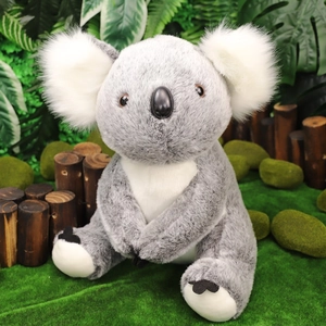 Peluche realistico di koala grigio e bianco su muschio naturale e ceppo d'albero
