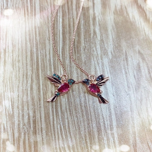Close-up of hummingbird earrings with rose gold plating and red pear-cut zircon stones