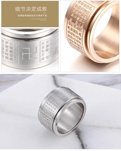 Detail of rotating stainless steel Buddhist Heart Sutra ring in silver and rose gold finishes