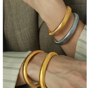 Close-up of gold and silver textured dragon scale bracelets layered on a wrist