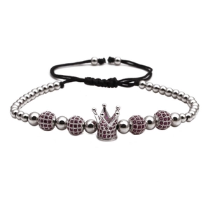 Detail of silver crown charm bracelet with dark red gemstone beads on adjustable cord