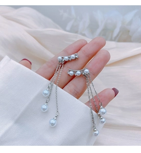 Detail of elegant silver tassel earrings with white pearls and long hanging chains