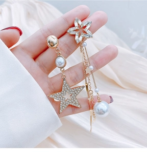 Macro shot of asymmetric star and pearl tassel earrings in gold-toned finish