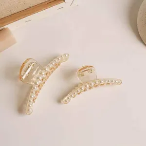 Detail of amber acrylic hair claws in two sizes with elegant faux pearl decorations
