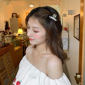 Elegant large pearl hair claw clip on model in a cozy indoor cafe setting