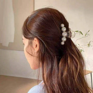 Detail of large pearl hair claw clip for women in an elegant half-up hairstyle