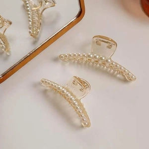 Close-up of amber resin hair claws featuring elegant white pearls in a dual set