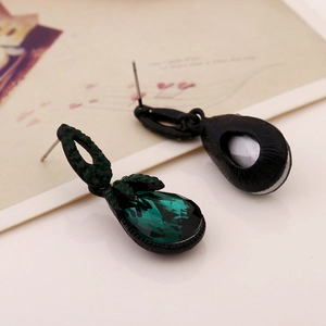 Close-up of bohemian dark green teardrop earrings with intricate black metal setting