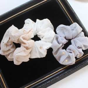 Three-piece chiffon hair scrunchies in beige, white, and grey with gold star patterns