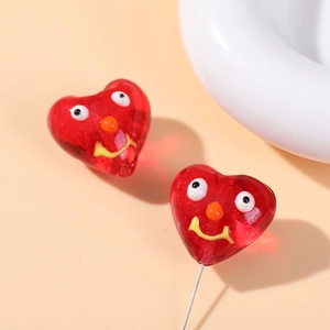 Macro shot of red heart glass bead with cute big eyes and yellow smiley face detail