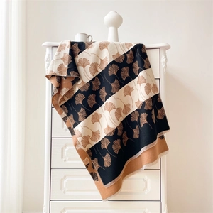 Detail of soft faux cashmere scarf featuring elegant black and beige ginkgo leaf patterns