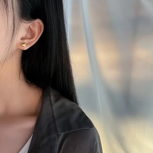 Polished 18K gold heart-shaped stud earrings shown on model for elegant minimalist style
