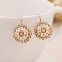 Detail of vintage gold flower rings with pearls and crystals on a white ceramic cup