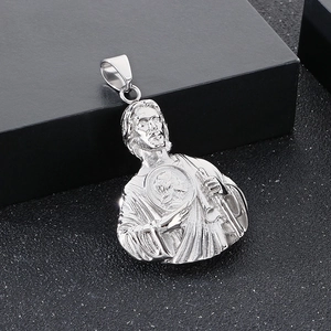Macro shot of silver Saint Jude pendant with heart relief and polished metal texture